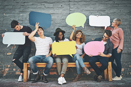 Shot of a diverse group of people holding up speech bubbles outside